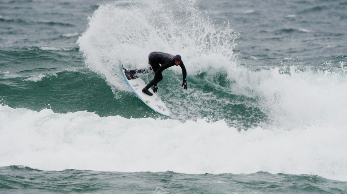 Surfer performing a maneuver on a wave in the ocean.