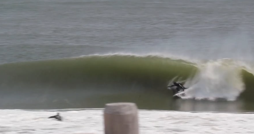 Surfer riding a large green wave with white foam.