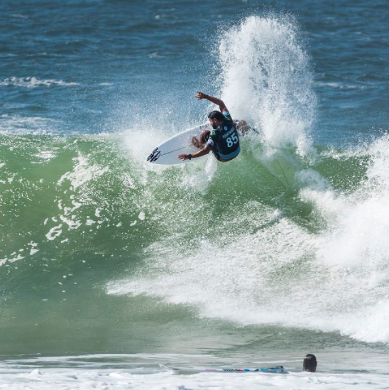 Surfer performing a trick on a large wave.