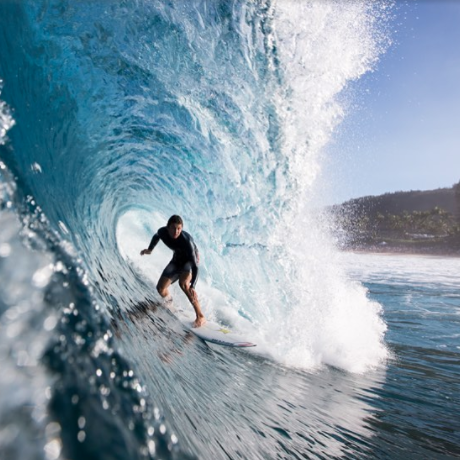 Surfer riding a wave inside a large barrel.