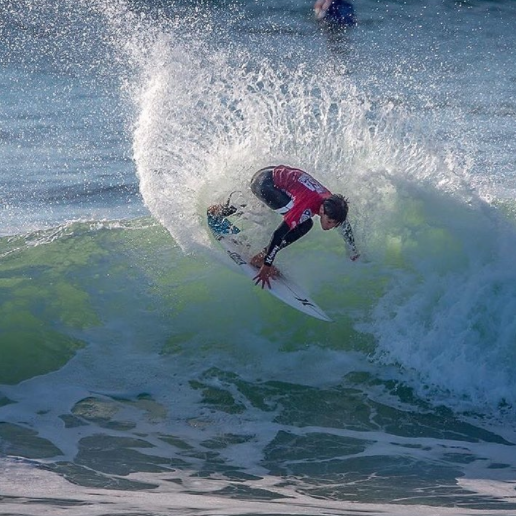 Surfer performing a maneuver on a green wave.