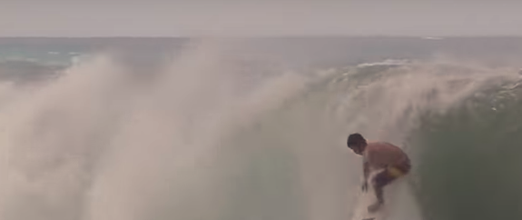 Surfer riding a wave with ocean in the background.