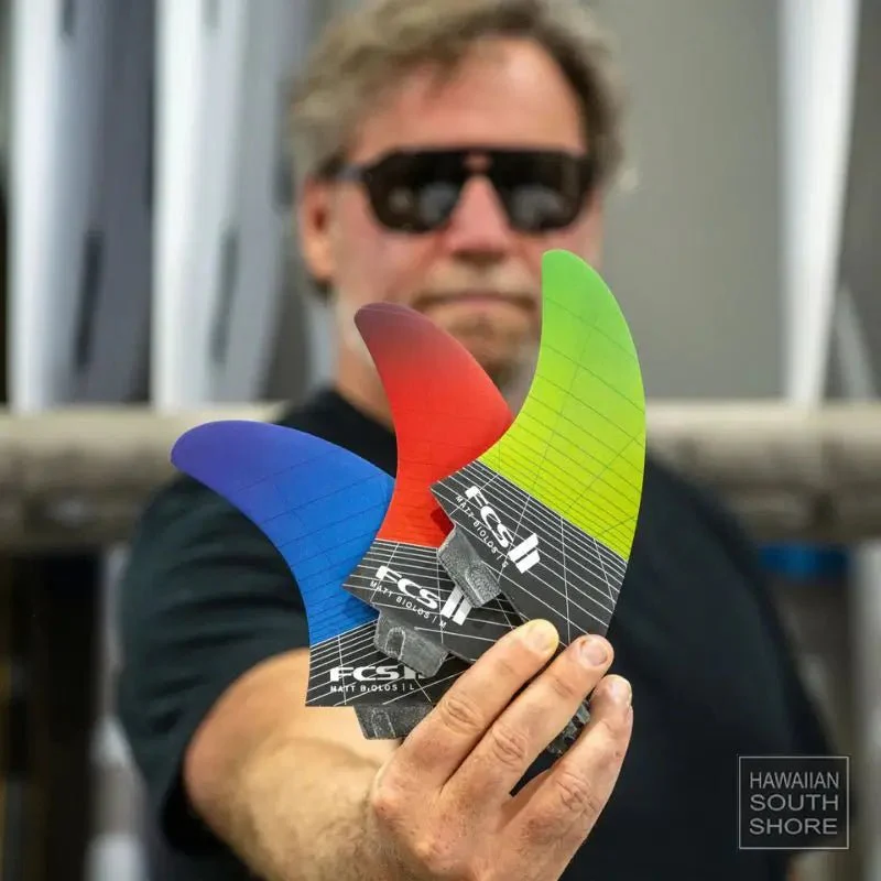 Man holding colorful surfboard fins in a workshop.